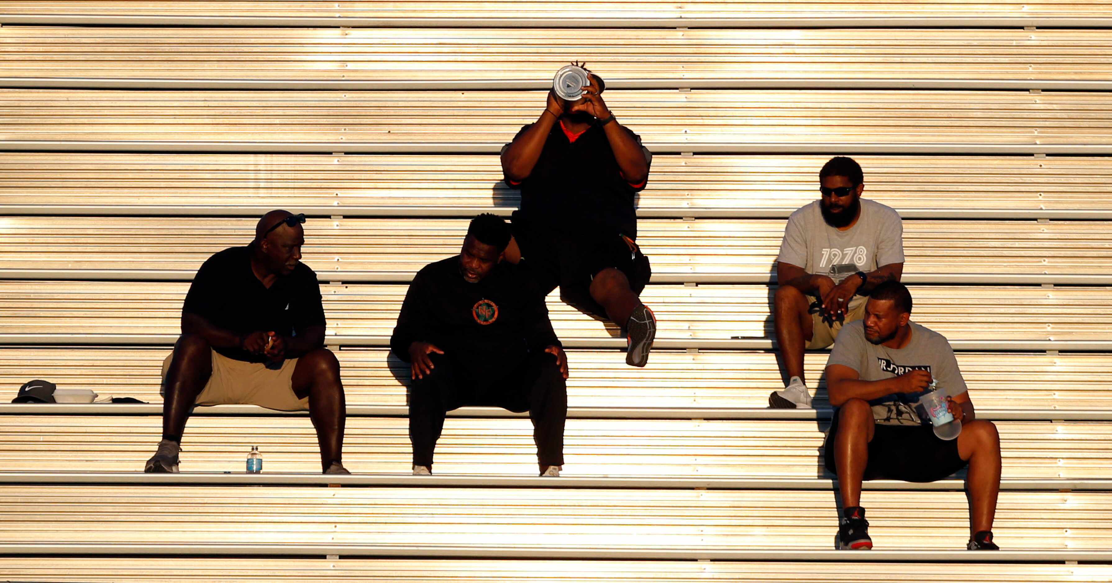 Fans are fried in the hot sun on the aluminum stands at Williams Stadium in Garland during...