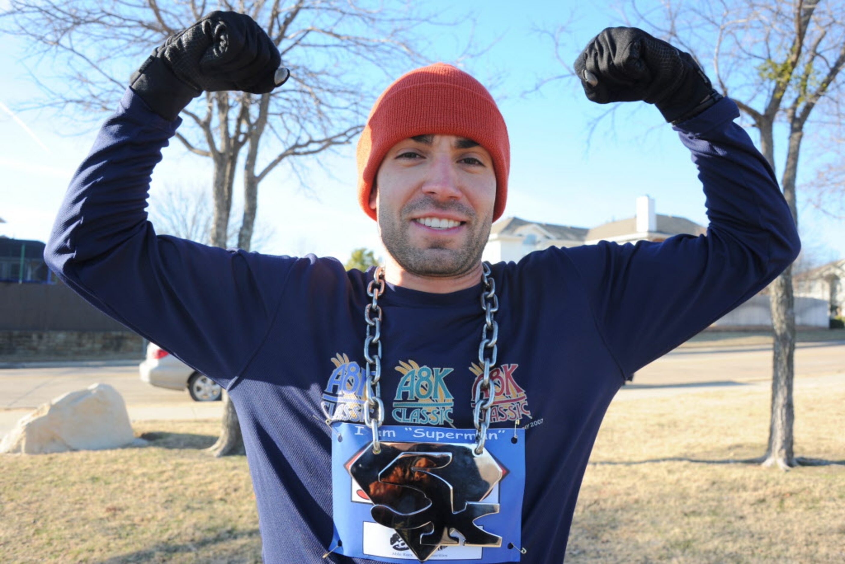 Overall men's first place runner Nick DeSantis flexes with his medal at the Superman 5k Run...