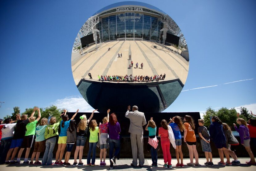 Butler Elementary fifth graders and AT&T Stadium Art Ambassador Phil Whitfield (center) wave...