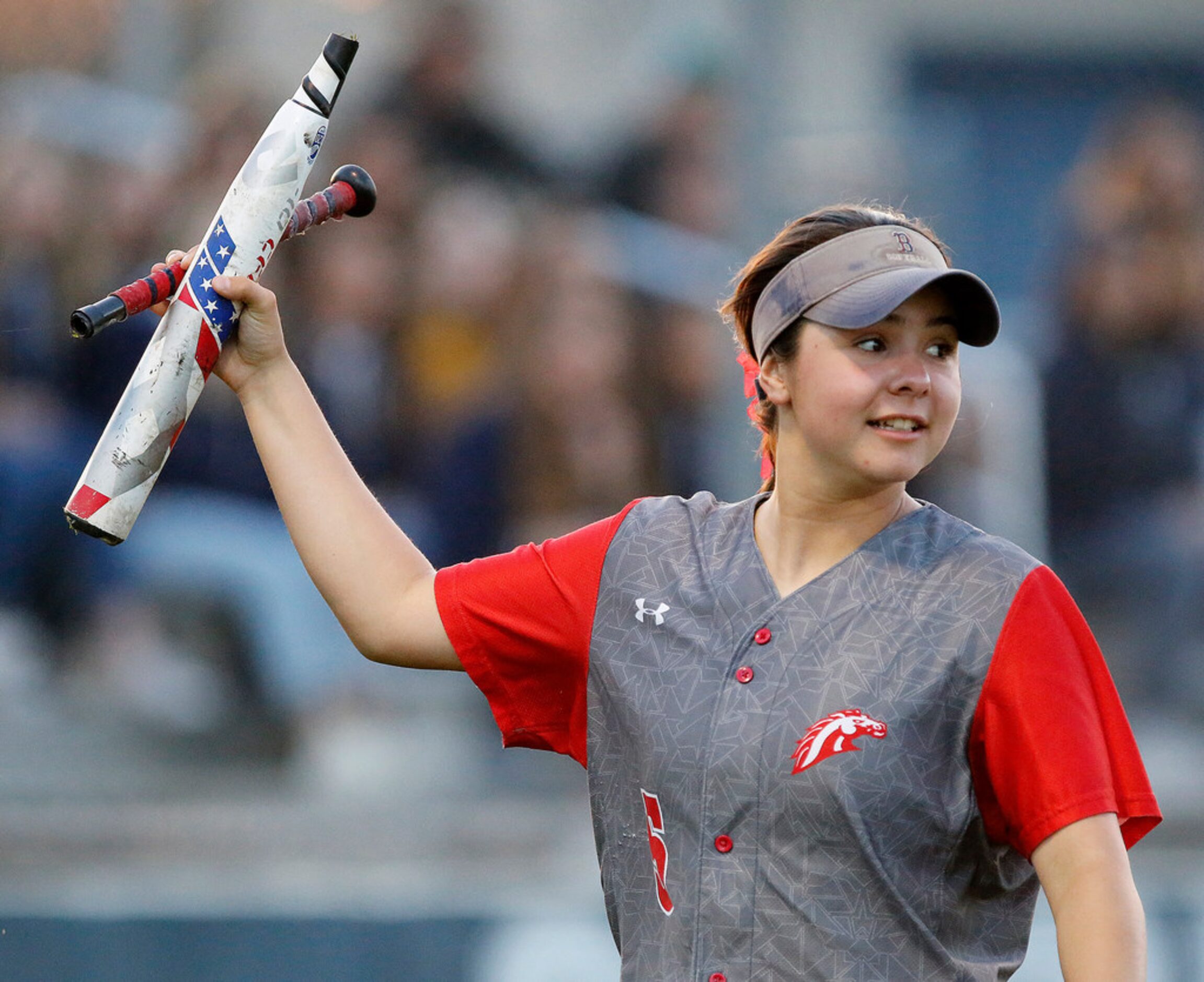 McKinney Boyd High School first baseman Anissa Lechner (5) retrieves a broken bat during the...