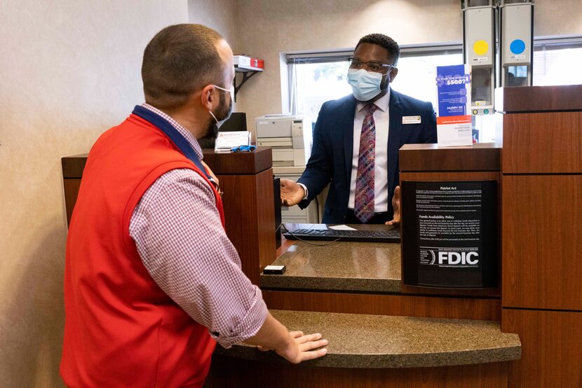 Banking center manager George Sloan (right) chats with financial specialist Aaron McAlister...