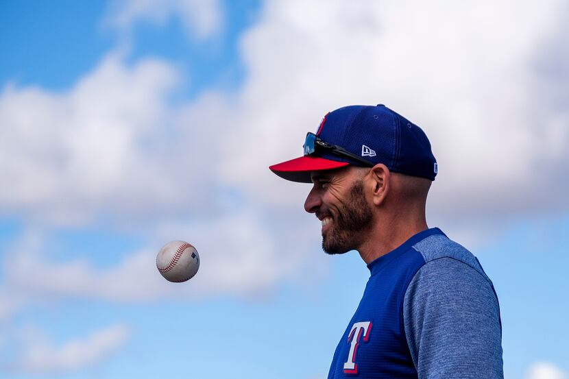 New Texas Rangers manager Chris Woodward tosses a ball as he watches his team during the...