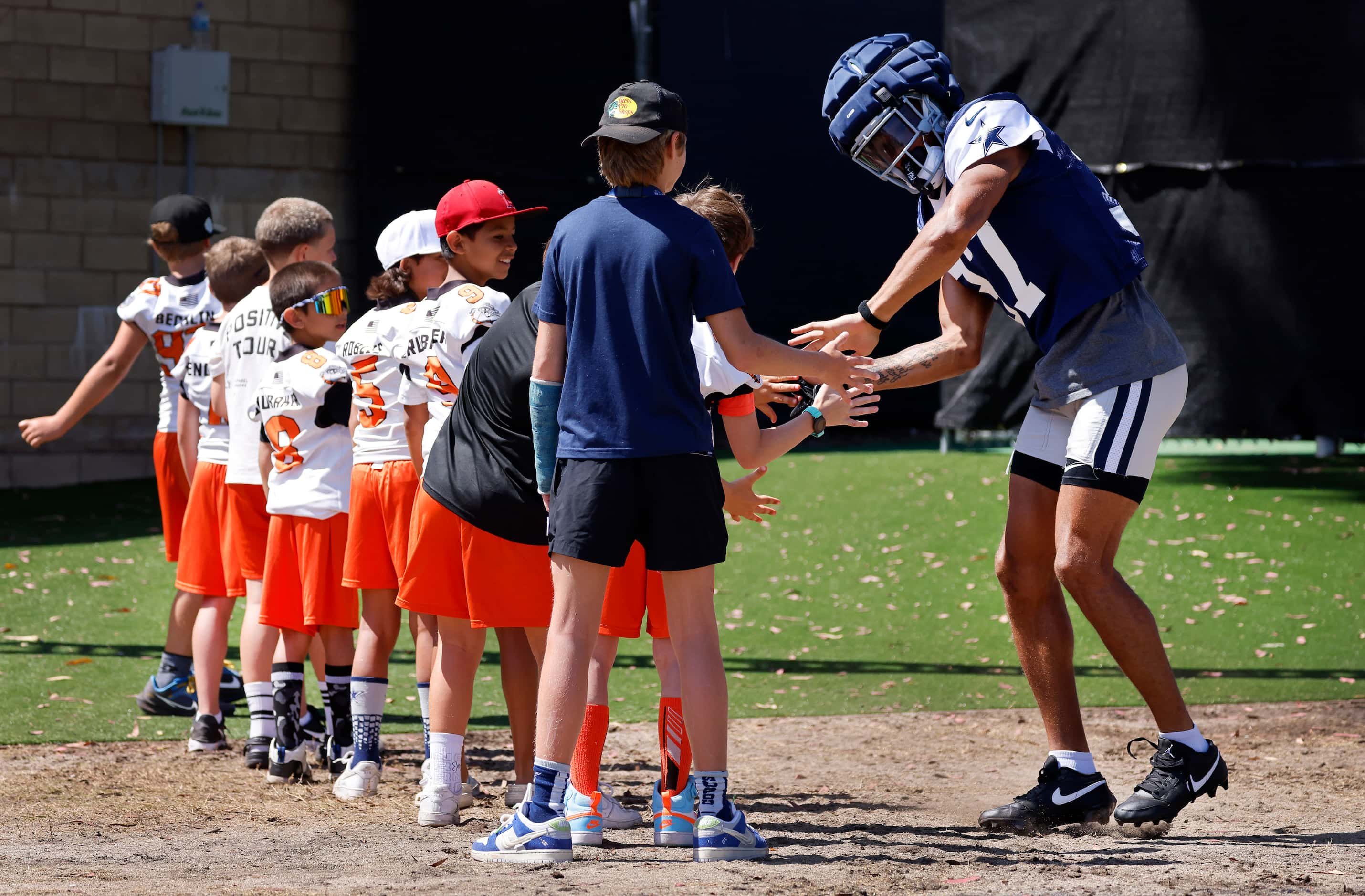 Dallas Cowboys cornerback Eric Scott Jr. (37) slaps hands with Simi Valley Bulldogs youth...