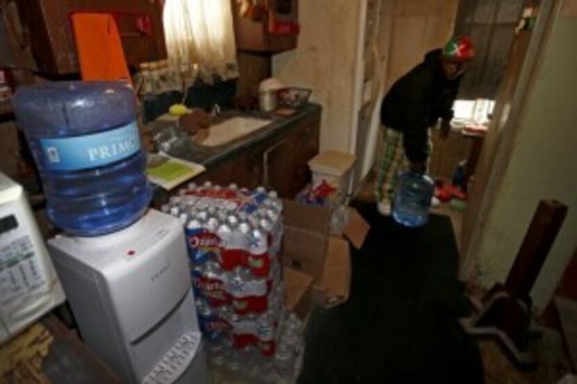 Resident Demetrius "People" Blair carries a 5-gallon water bottle that the county and a...