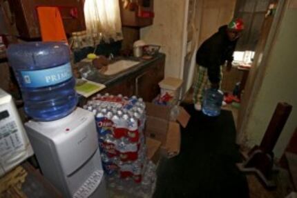  Resident Demetrius "People" Blair carries a 5-gallon water bottle that the county and a...