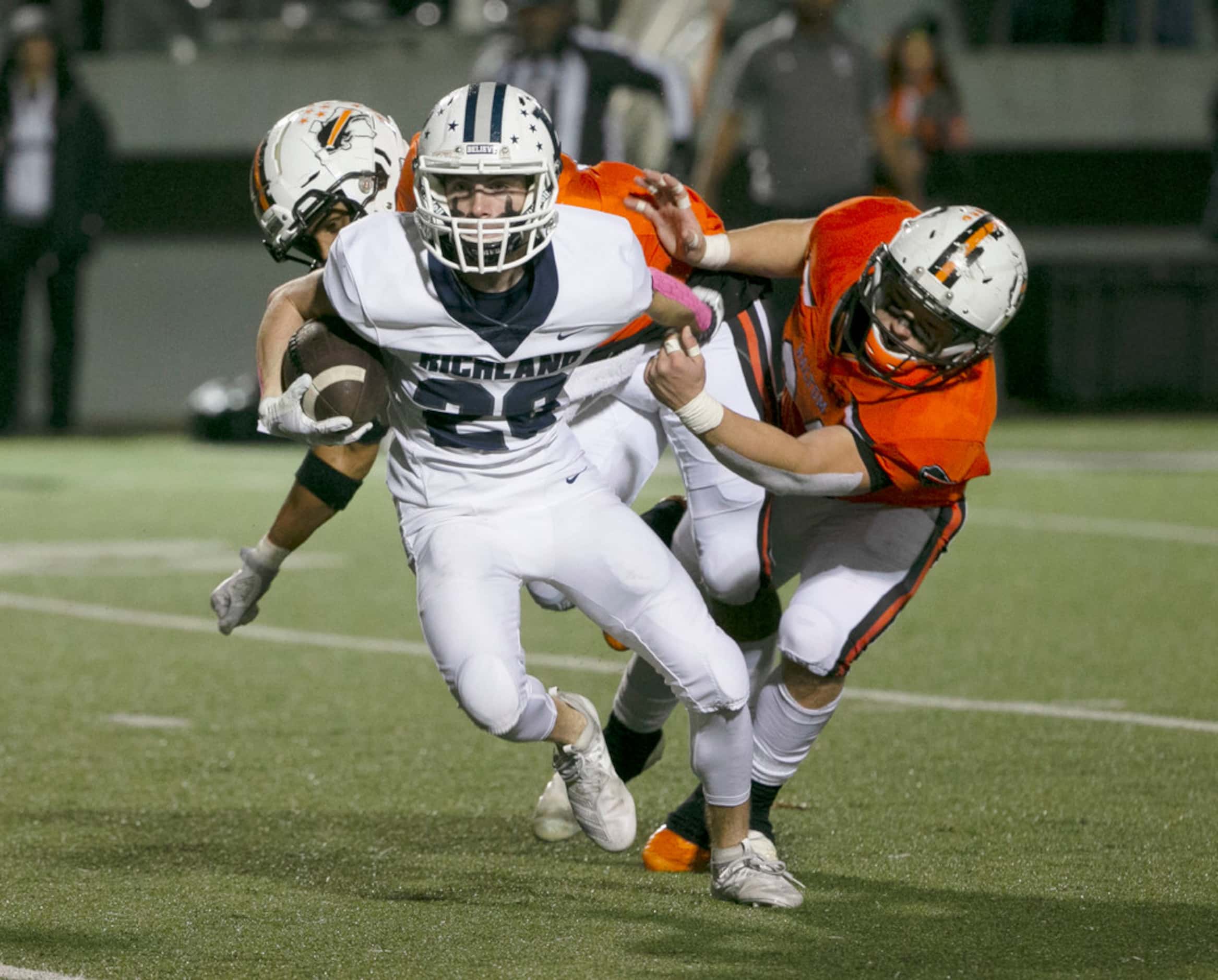 Richland's Slade Hamilton (20) break away from an attempted tackle by two Haltom defenders,...