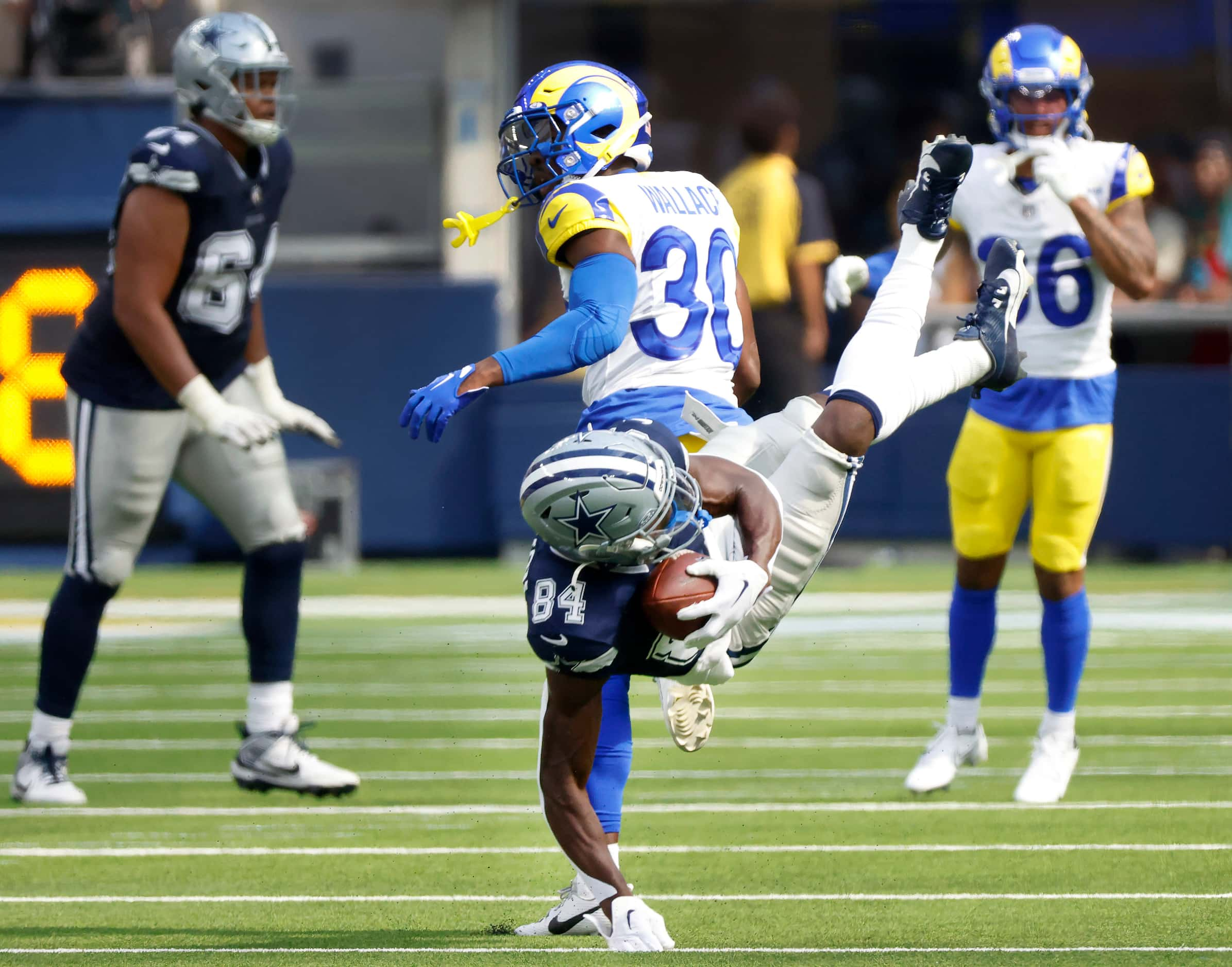 Dallas Cowboys wide receiver Kelvin Harmon (84) is upended by Los Angeles Rams cornerback...