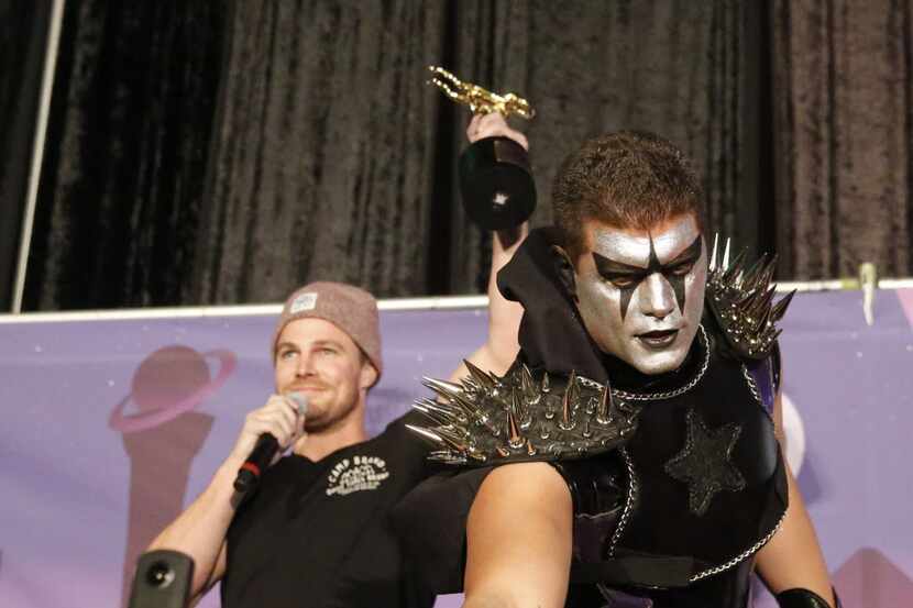 Stephen Amell, left, holds up a wrestling trophy as WWE superstar Stardust reaches for a...