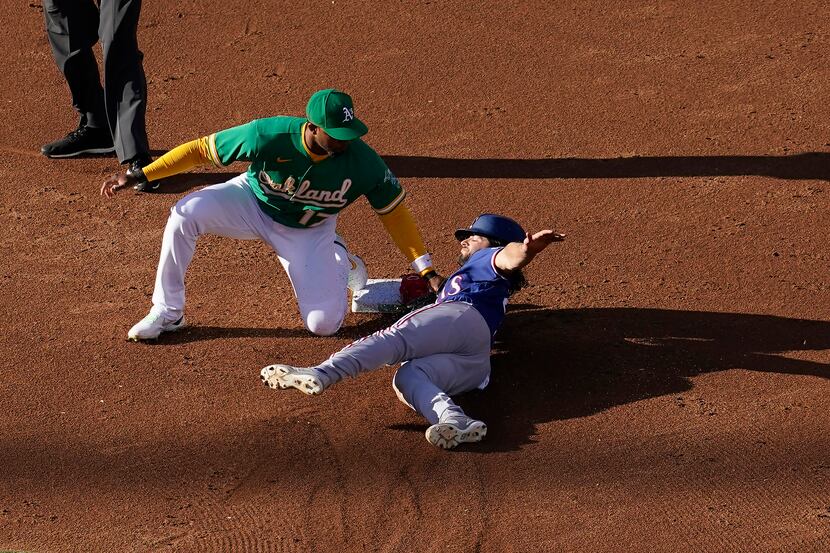 Texas Rangers' Josh Smith, right, is tagged out by Oakland Athletics shortstop Elvis Andrus...