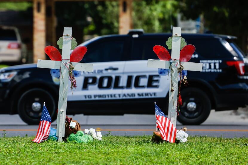 A Uvalde police SUV passes by a memorial in honor of the 21 victims of a mass shooting at...