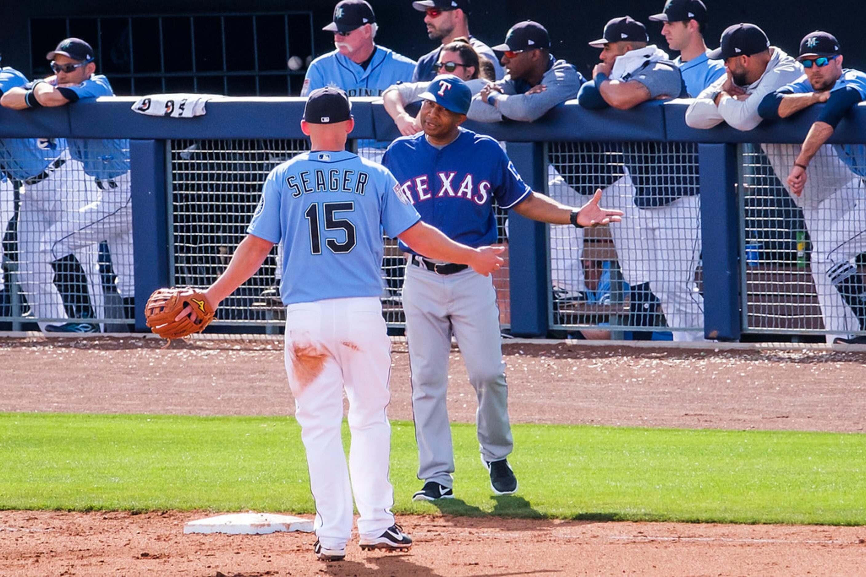 Texas Rangers third base coach Tony Beasley jokes with Seattle Mariners third baseman Kyle...