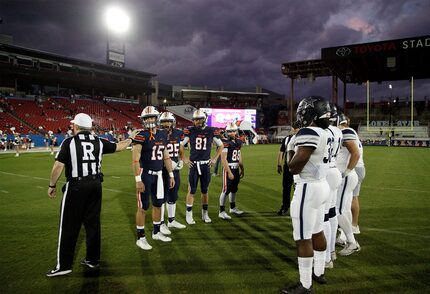 Team captains meet at midfield for the coin toss under ominous clouds as Wakeland High...