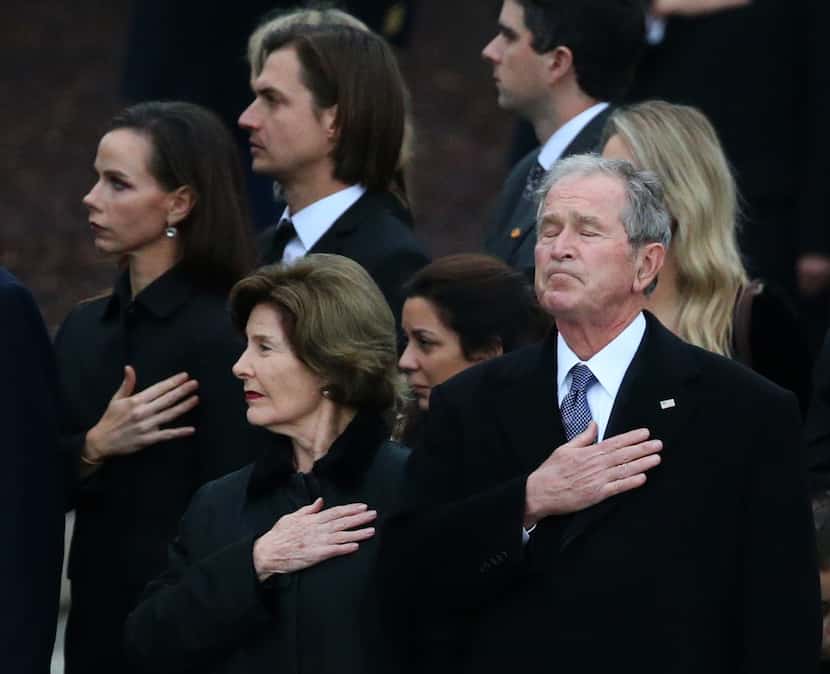 Former President George W. Bush reacts alongside his wife Laura Bush as the flag-draped...
