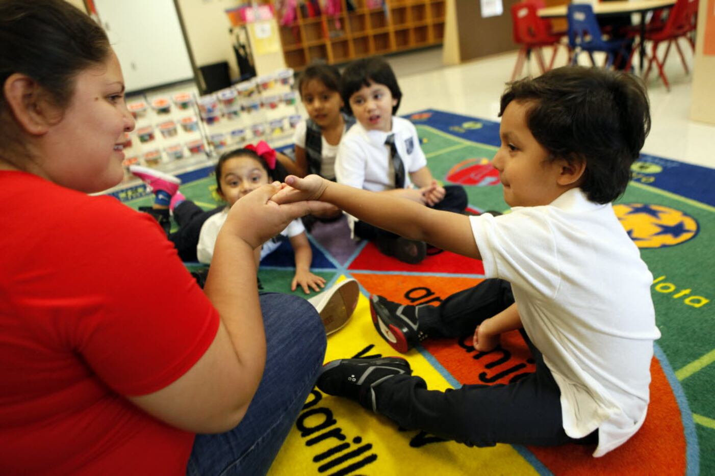 Pre-K bilingual teacher Elizabeth Villalta holds the hand of 3-year-old Nicholas Jaramillo...
