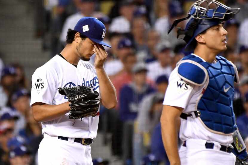 Los Angeles Dodgers starting pitcher Yu Darvish looks down after giving up a double to the...