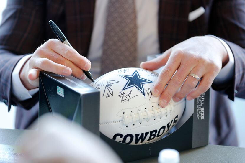 Dallas Cowboys Jason Witten signs a football for a fan at Naval Air Station Point Mugu in...