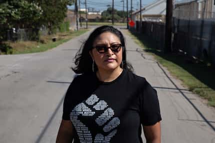 Janie Cisneros stands for a portrait between her neighborhood and the GAF shingle...