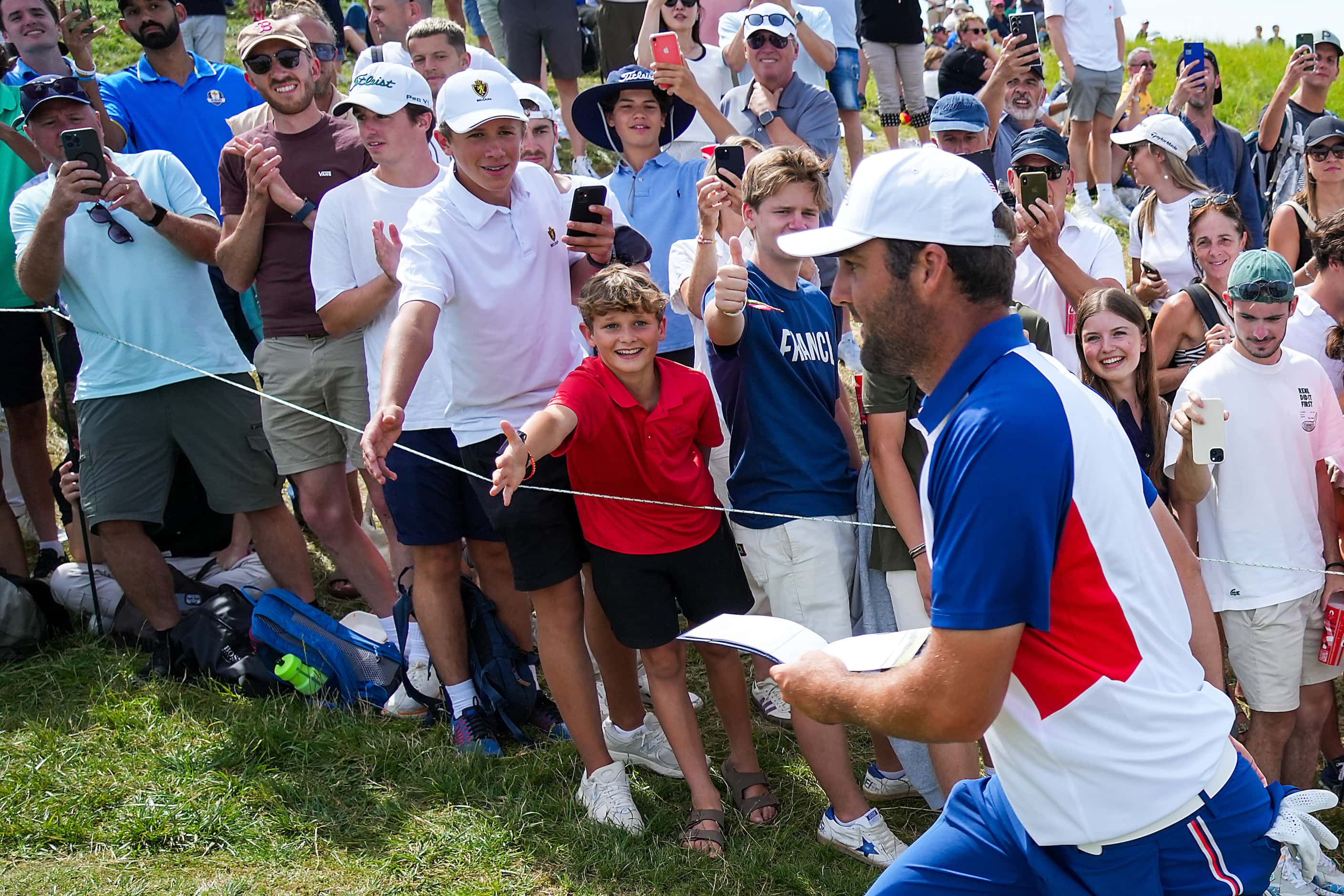 Fans reach out to Scottie Scheffler of the United States as he walks between holes during...