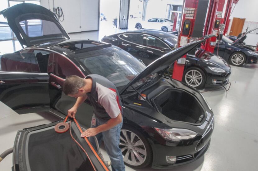 Rick Hynes, a Tesla vehicle technician,  replaces the weather stripping on the sunroof lid...