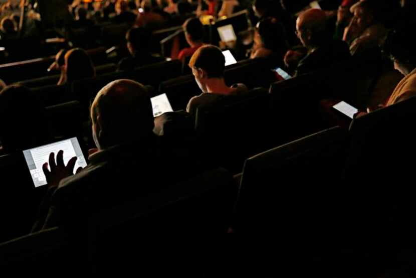 
New Cities Summit participants work on their tablets and smartphones during a session at...