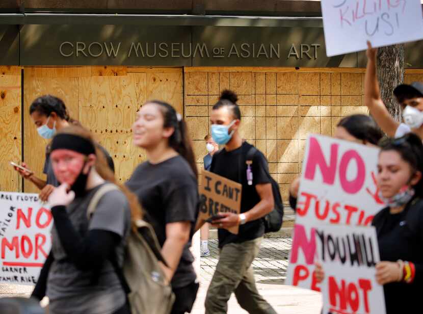 Protestors supporting Black Lives Matters march past the boarded up Crow Museum of Asian Art...