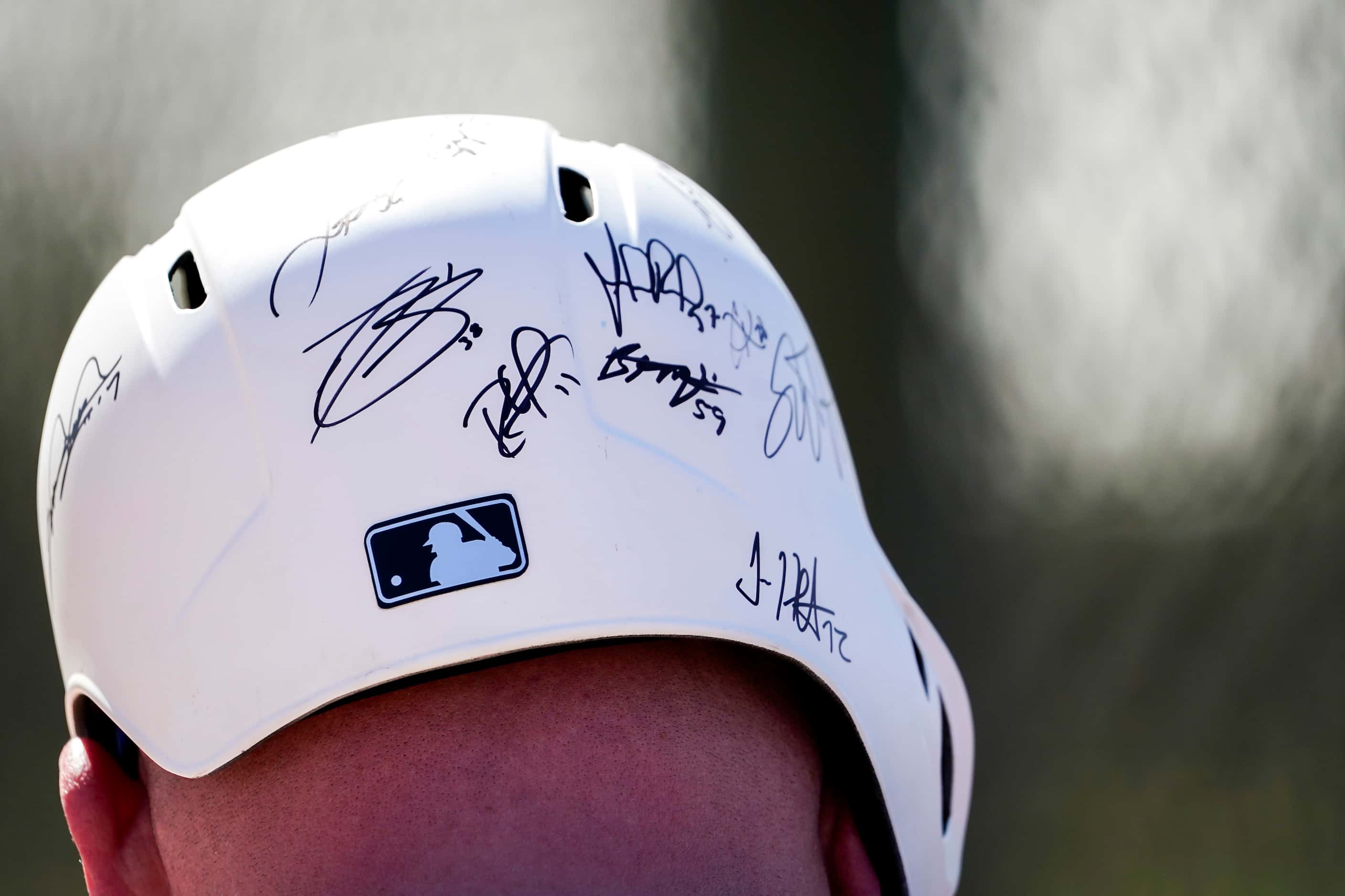 A fan sports a helmet filled with autographs, from Texas Rangers players during a spring...