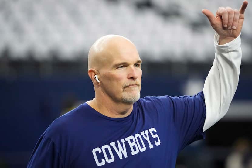 Dallas Cowboys defensive coordinator Dan Quinn gestures to fans as the teams warm up before...