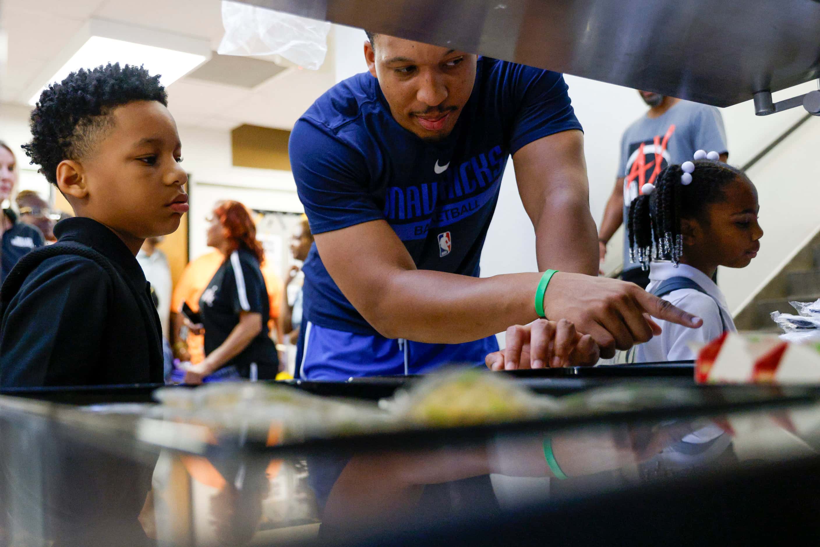 Dallas Mavericks forward Grant Williams (center) helps pass out breakfast to students during...