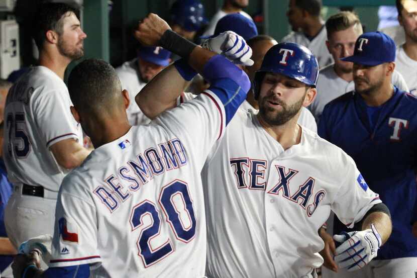 The Texas Rangers' Ian Desmond (20) bumps elbows with Mitch Moreland, who hit his second...