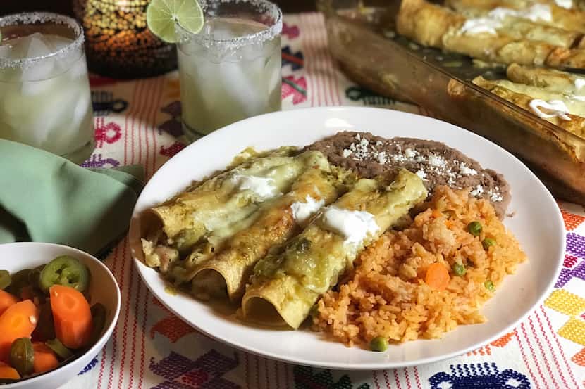 A plate of enchiladas verdes, Mexican rice and refried beans