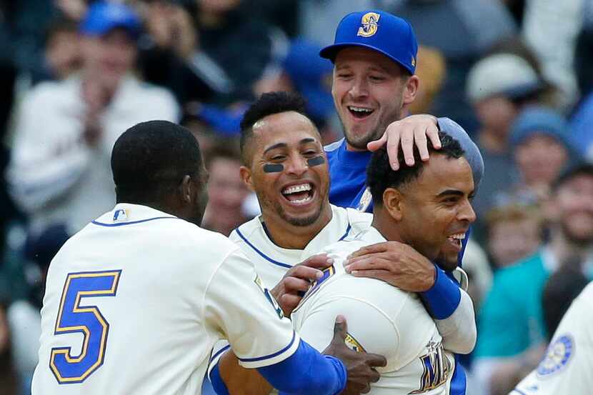 Seattle Mariners' Nelson Cruz, right, is greeted by teammates including Leonys Martin,...