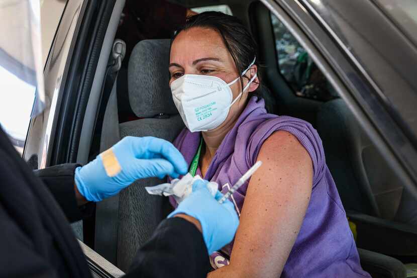 Nurse Lisa Wheeler administers a dose of the Pfizer-BioNTech COVID-19 vaccine to Cristina...