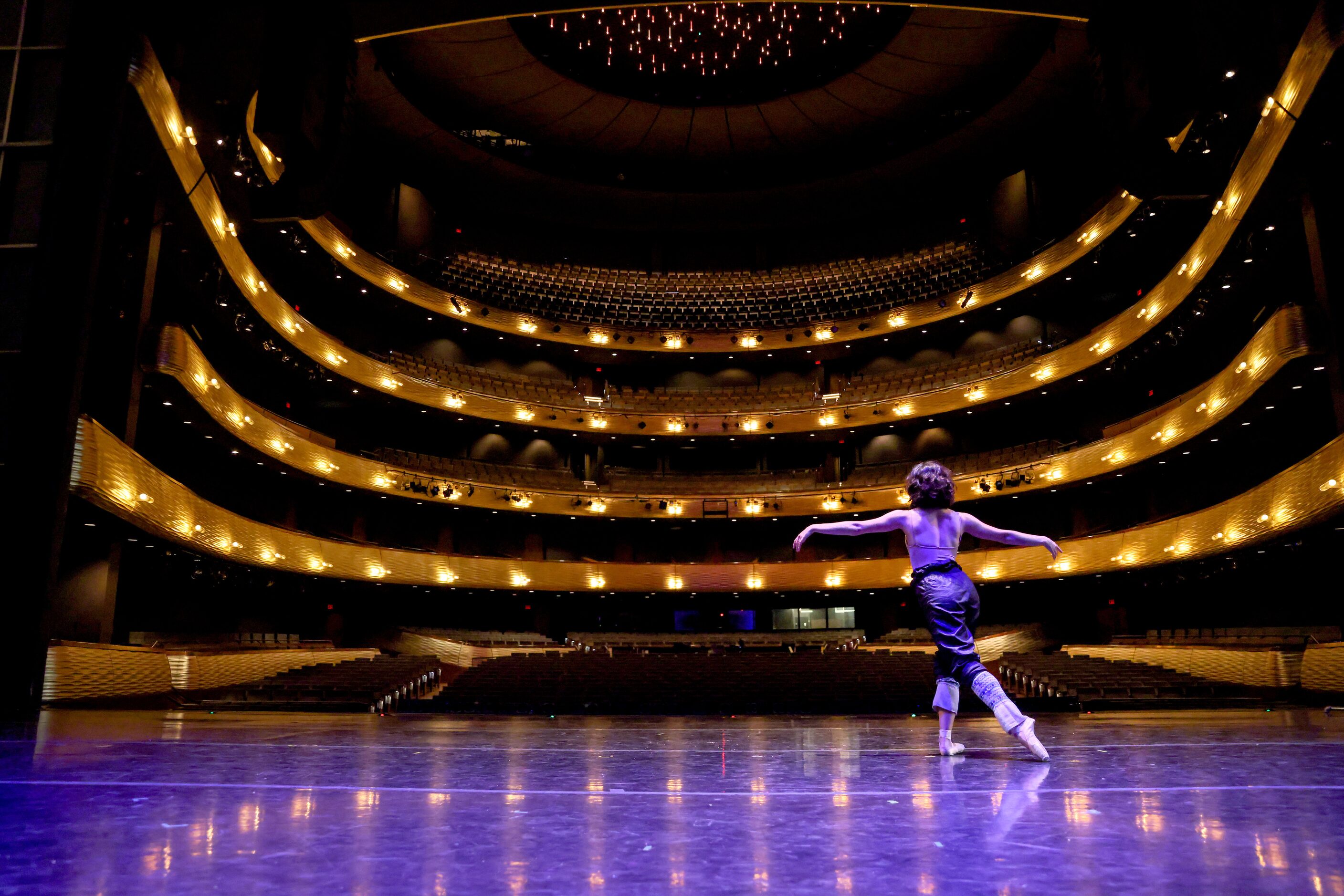 Alexandra F. Light transitions to her pointe shoes as she warms up on an empty stage for her...