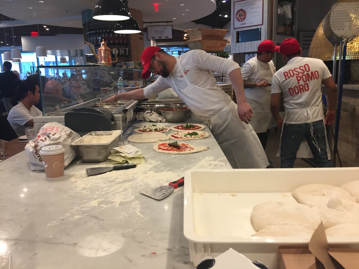 Eataly pizza ovens and marble slab counters are open to the restaurant, adding to the...