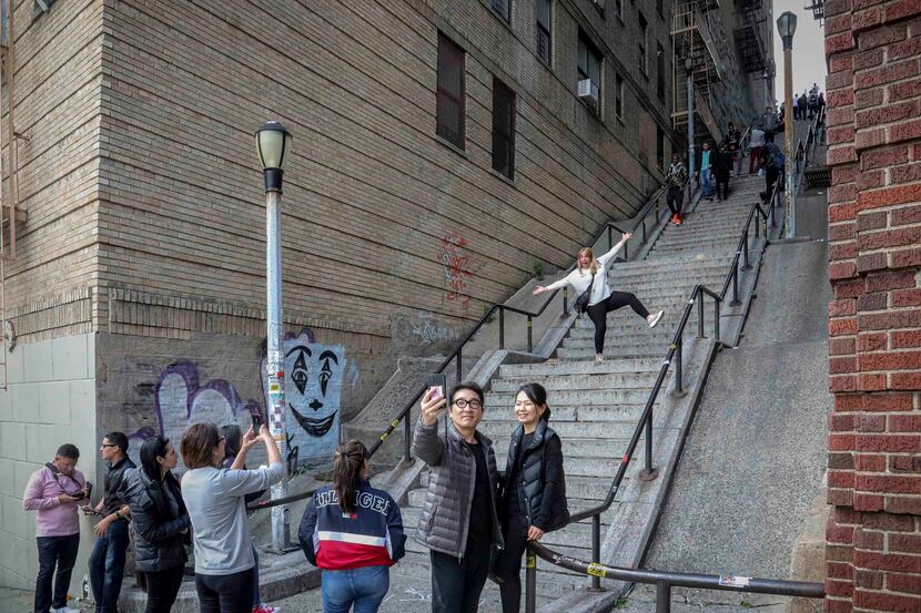People pose on the steps between two apartment buildings in the Bronx made famous by "Joker."