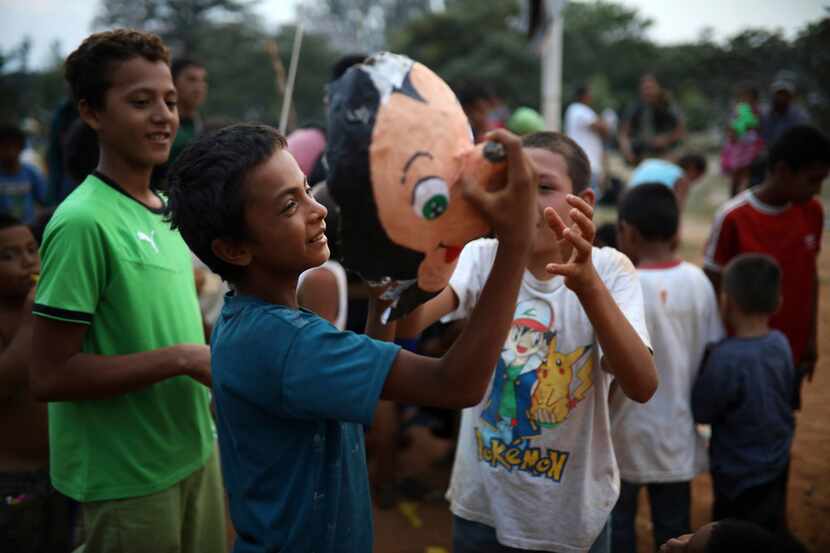 Children play with the face of a Mickey Mouse pinata, at the sports club where Central...
