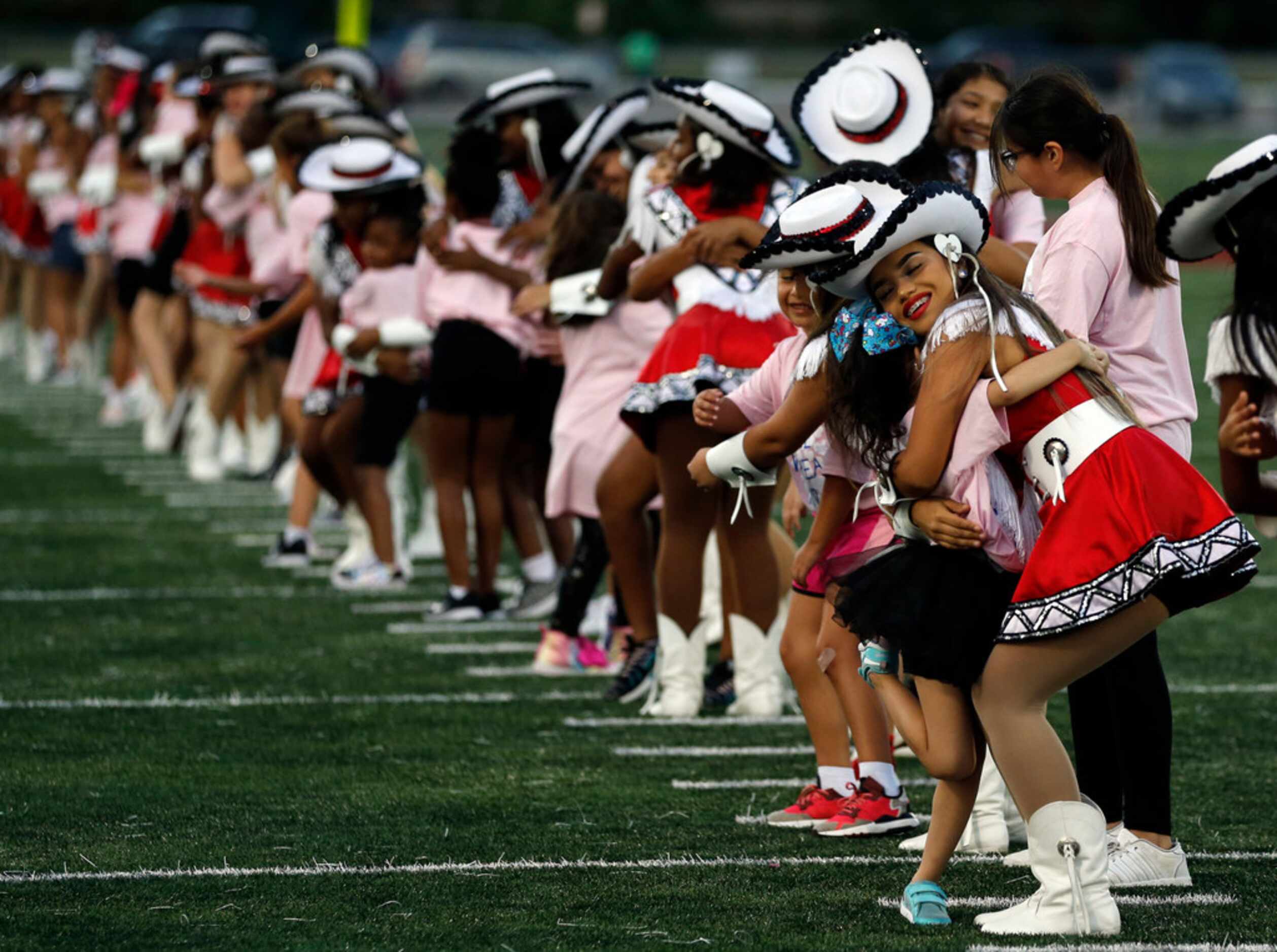 The Mesquite Horn drill team, the Scarlet Sweethearts, hug little guest girls that performed...