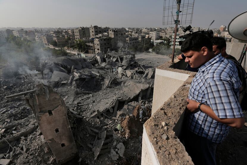 A Palestinian, standing on an adjacent building, inspects the rubble of the Imam Al Shafaey...