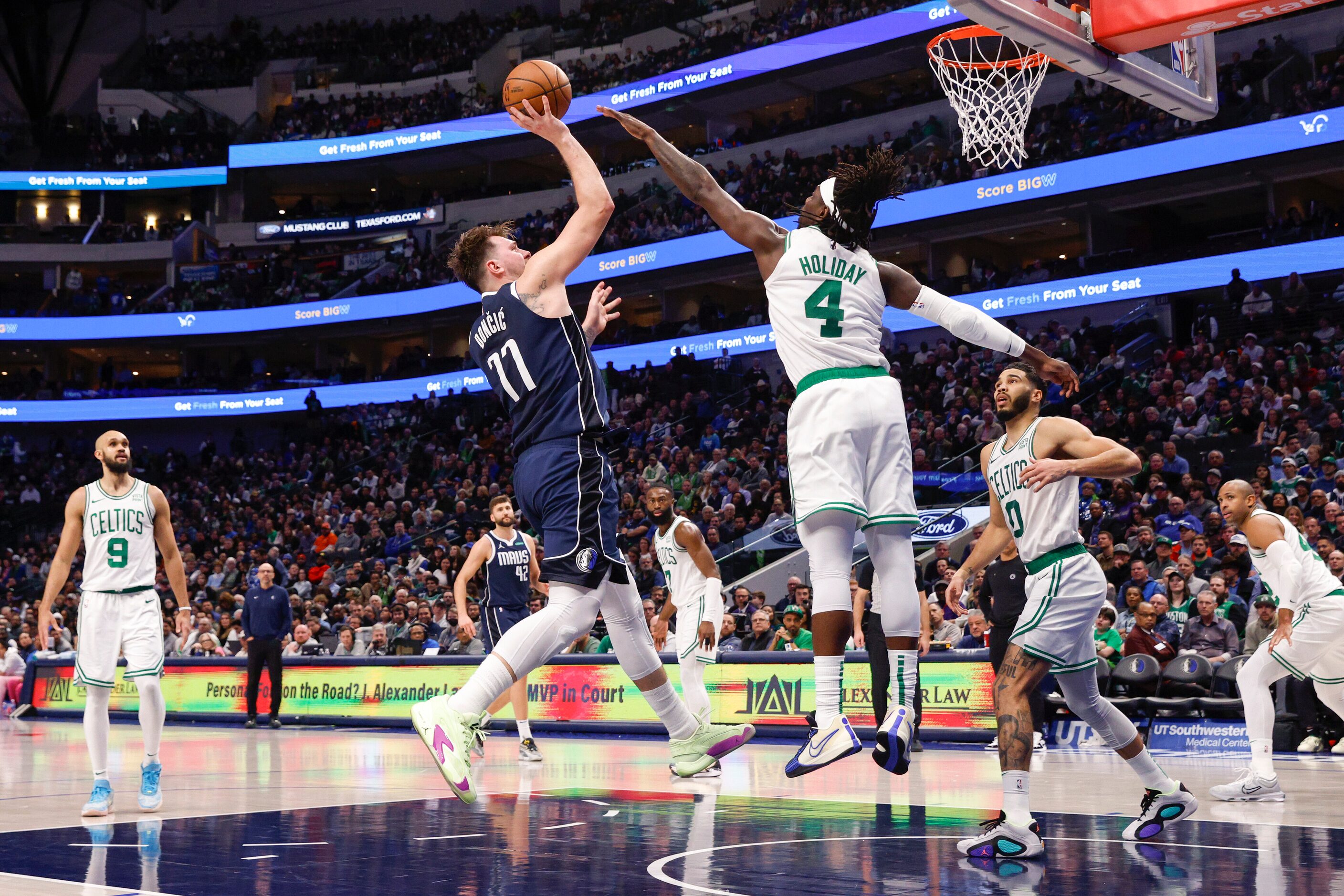 Dallas Mavericks guard Luka Doncic (77) shoots over Boston Celtics guard Jrue Holiday (4)...