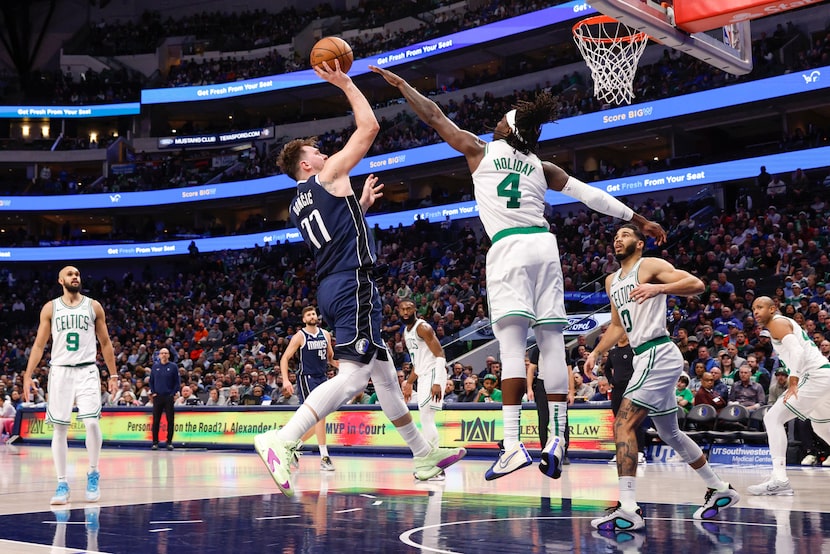 Dallas Mavericks guard Luka Doncic (77) shoots over Boston Celtics guard Jrue Holiday (4)...