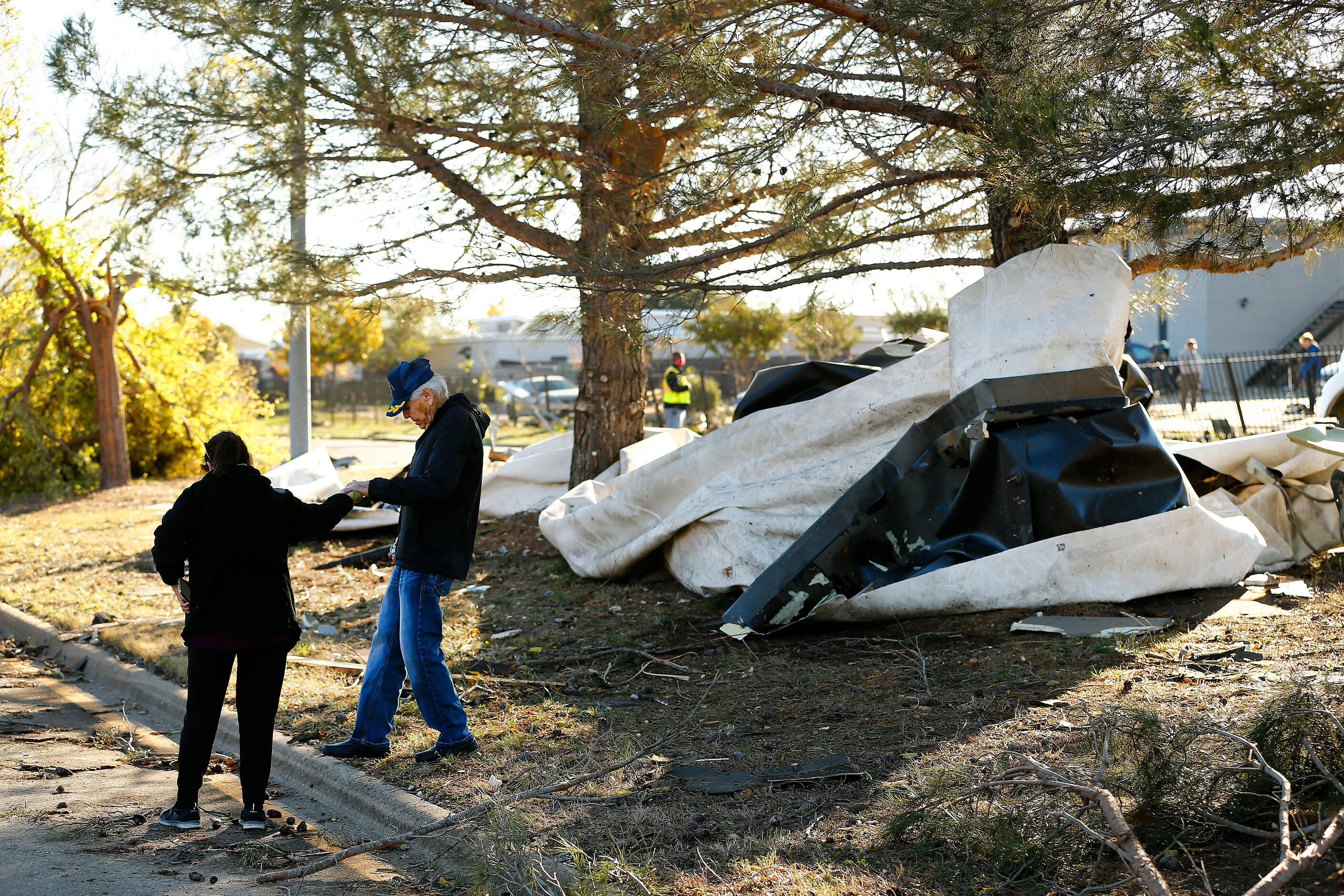 Anna Barrera helps her husband down the curb as they inspected the damage form a...