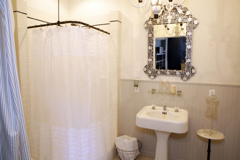 A bath features a black and white bone inlay mirror.