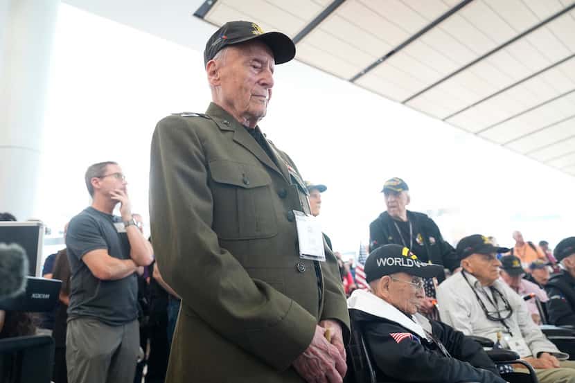 World War II veteran Bob Hartline stands and listens to a speaker before boarding a plane...