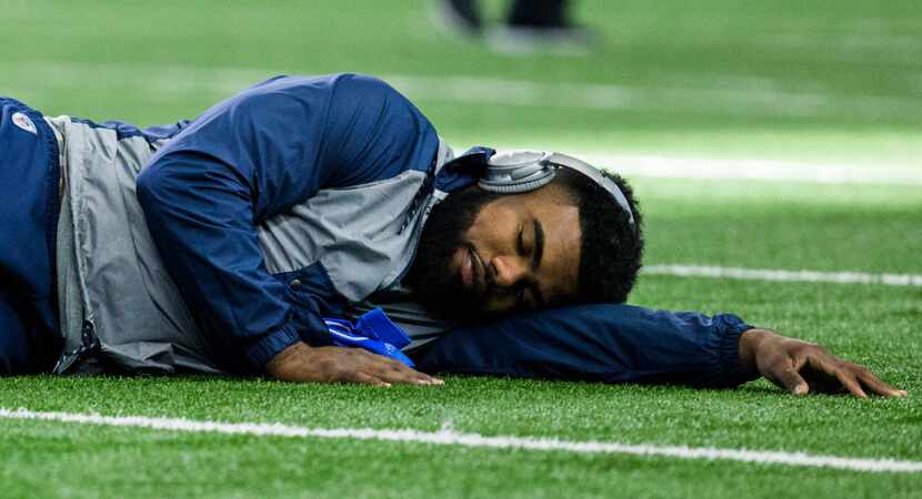 Dallas Cowboys running back Ezekiel Elliott (21) rests on the turf as he warms up before...