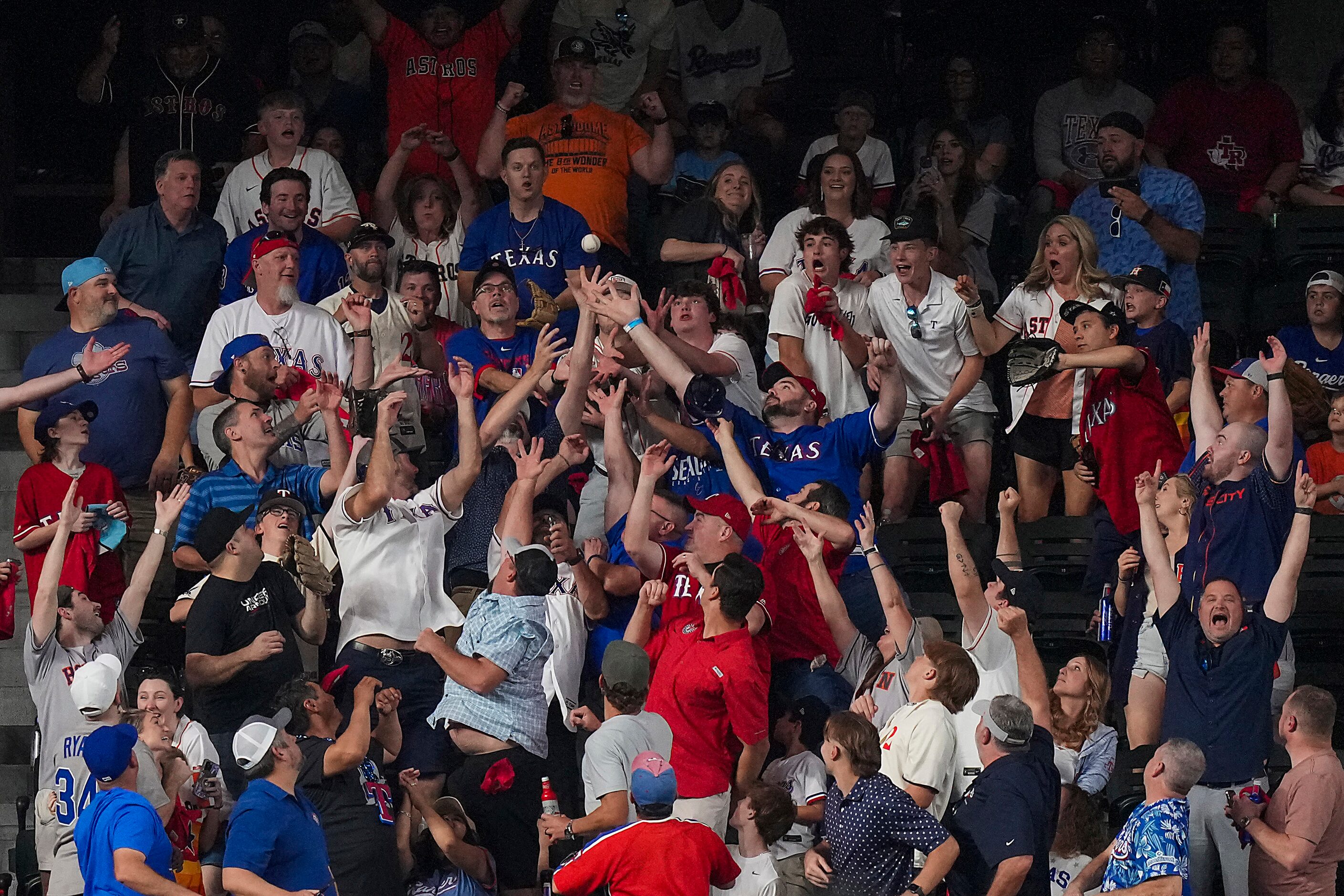 Fans reach for a home run off the bat of Houston Astros third baseman Alex Bregman during...