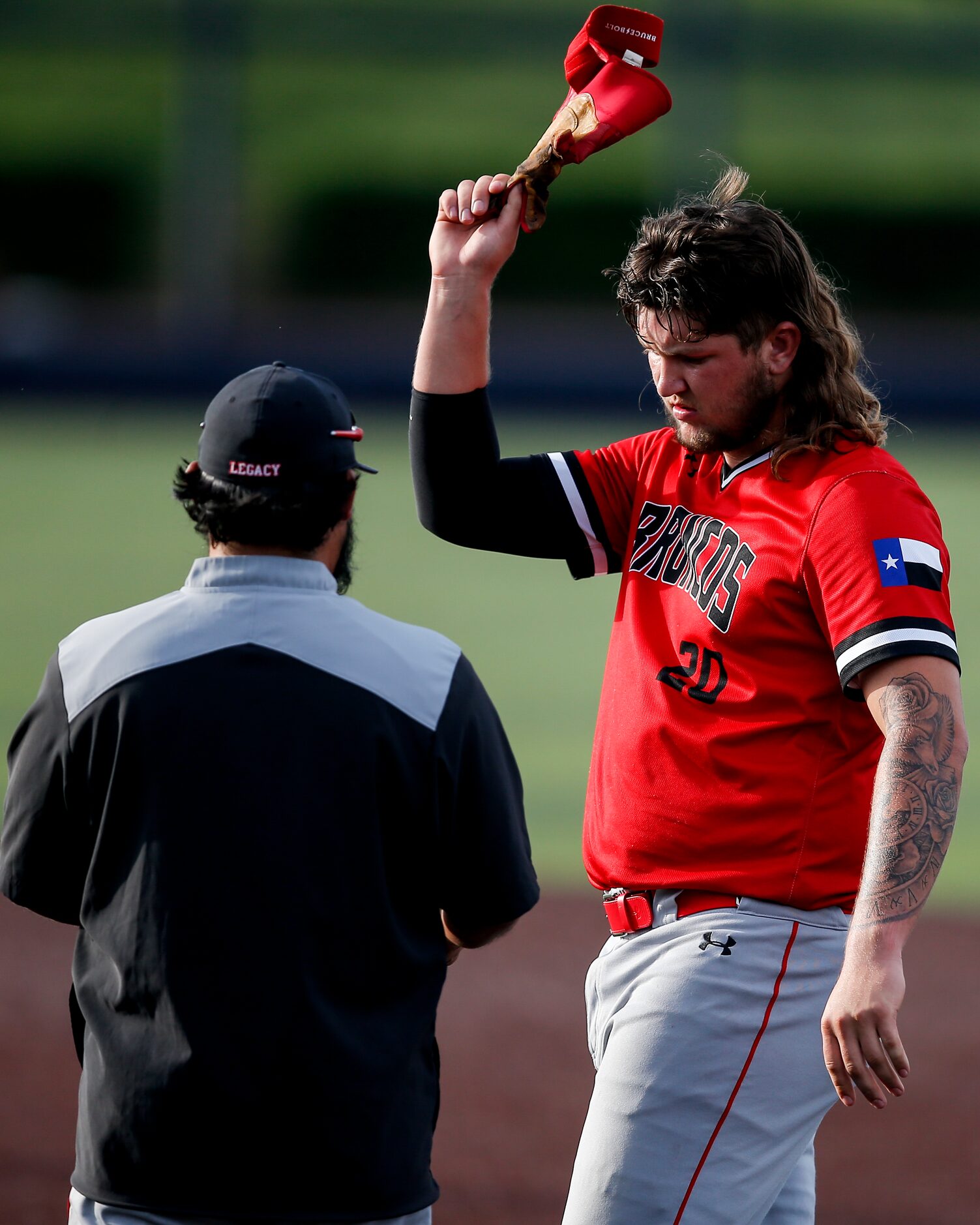 Mansfield Legacy’s Kayden Voelkel (20) throws his batting glove into his helmet, held by the...