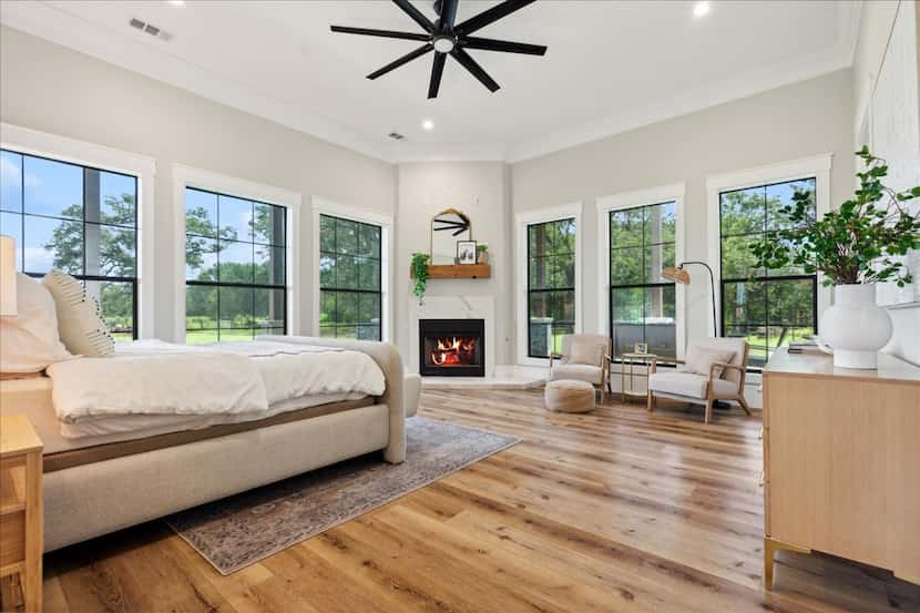 Bedroom with numerous windows, fireplace in corner and bed on opposite wall