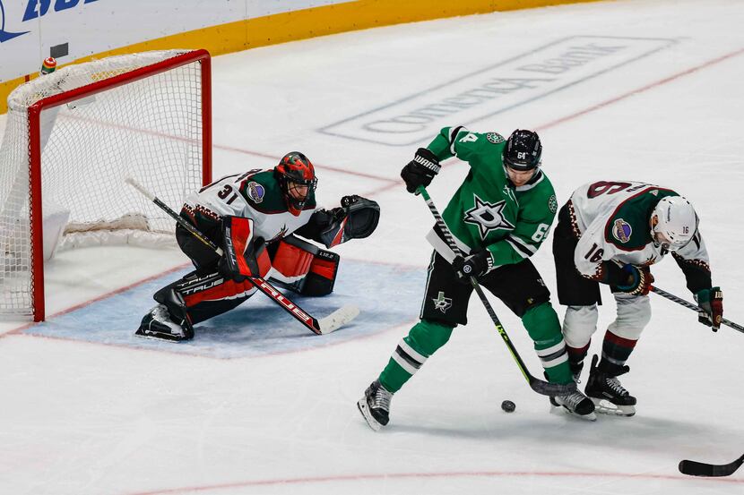 Dallas Stars center Tanner Kero (64) tries to get control of the puck from Arizona Coyotes...