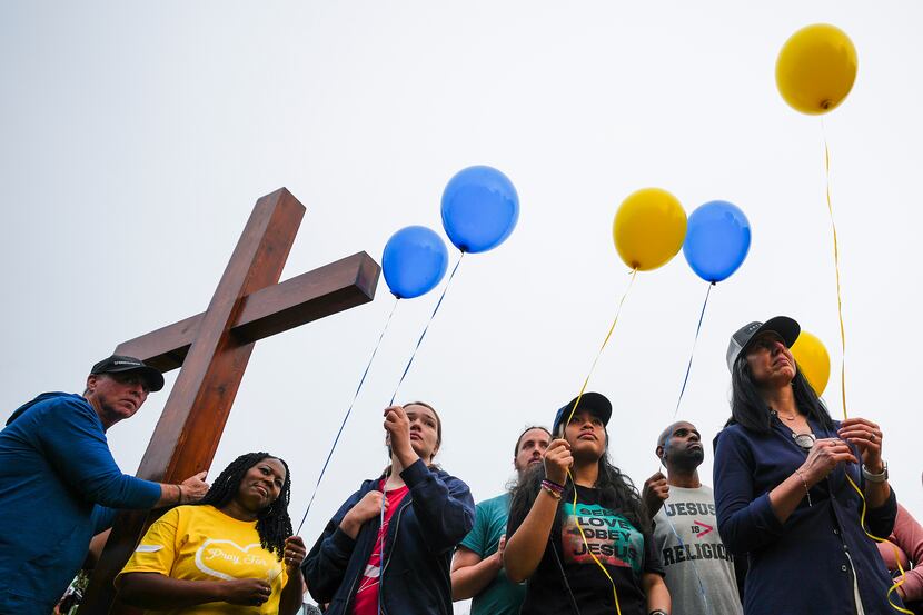 People prepare to release balloons during a vigil at a memorial to victims of the mass...