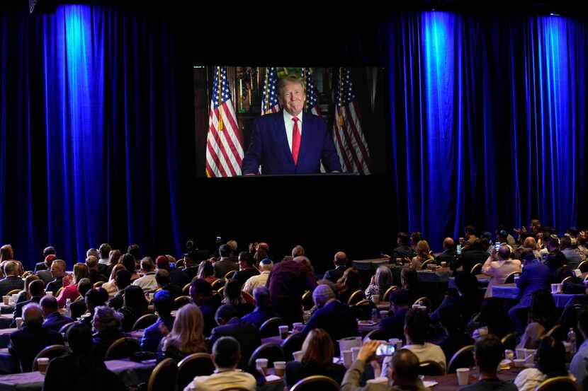 FILE - People listen as former President Donald Trump speaks remotely to an annual...